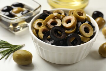 Different delicious marinated olive rings and whole ones on light table, closeup