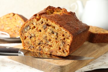 Cut homemade carrot cake with nuts and knife on table, closeup