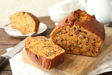 Cut homemade carrot cake with nuts and knife on wooden table, closeup
