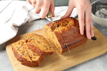 Woman cutting homemade carrot cake at grey table, closeup