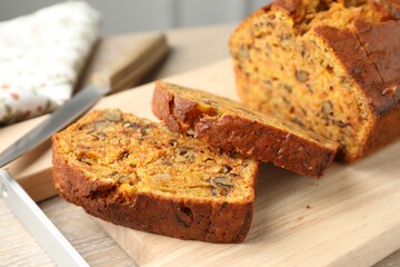 Cut homemade carrot cake with nuts and knife on wooden table, closeup