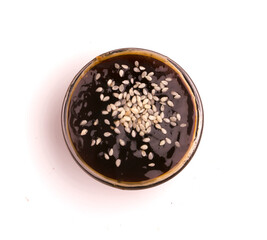 bowl of teriyaki sauce and sesame seeds on a white background