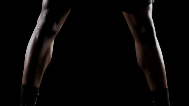 Basketball player bouncing a ball. African american sports man practicing against black background. Abstract body shot front view.