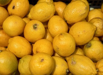 Ripe fresh yellow lemons on the shelf of a fruit supermarket are displayed for sale