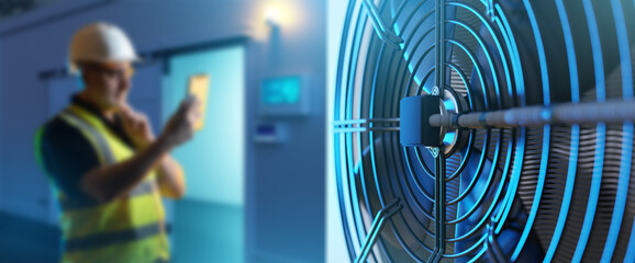 Industrial refrigeration equipment. Air conditioning unit for freezer warehouse. Man with laptop is...