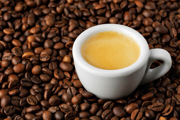 white espresso cup stands on roasted beans, highlighting rich crema and creating perfect background for coffee lovers