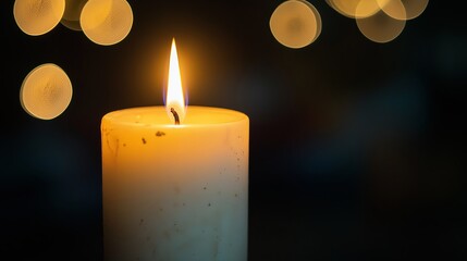 A single white candle with a soft flame in the center of the frame