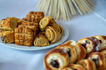 A plate of baked sourdough, including tarts with curd and plum jam, as well as other small, golden brown cakes with seeds and cheese frosting. 