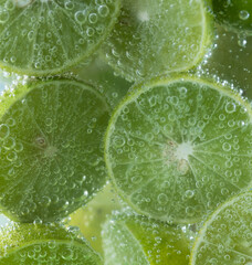 Close up of fresh lime slice in sparkling water with bubbles
