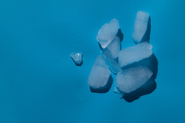 Ice cubes with water drops on light blue background,hard light with shadows
