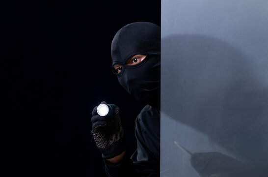 Studio shot of a stealthy thief breaking into a room and carefully looking around isolated on black background