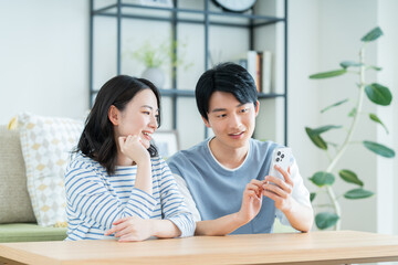 リビングでスマホを見る若い夫婦