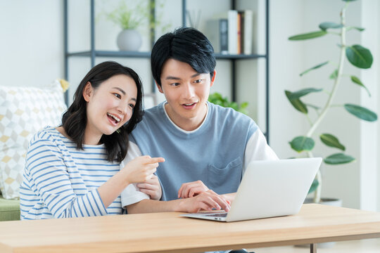 リビングでパソコンを見る若い夫婦