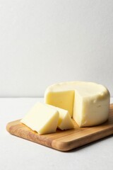 A creamy round cheese displayed on a light wooden board, presented with several triangular slices for a delectable dairy delight