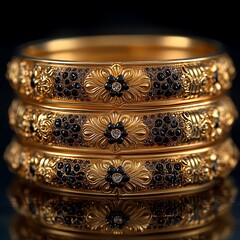 Three elegant gold bangles with intricate floral patterns and black stones on a dark background