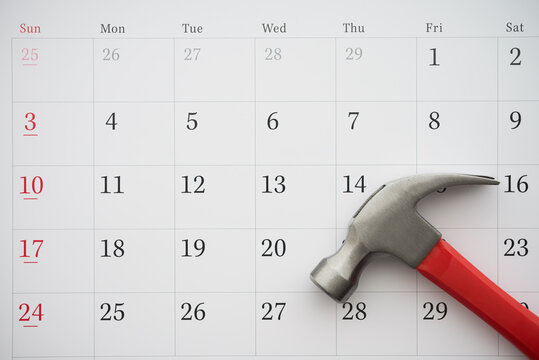Flat lay of hammer on blank white calendar background copy space. DIY, home improvement, repair schedule and planning, construction industry and so on concept.