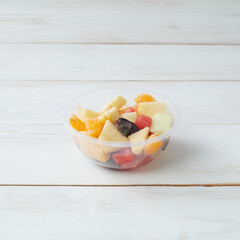 Fresh Fruit Salad Featuring Colorful Cut Fruits in a Plastic Bowl on a Wooden Table