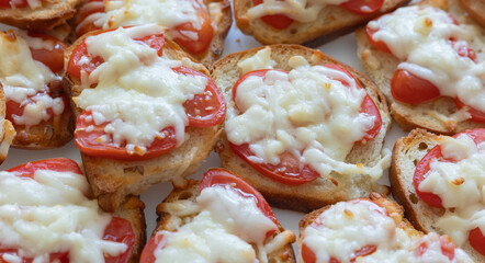 Tasty sandwiches with tomato and cheese on white bread.