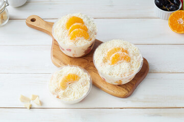 Fresh Fruit Salad With Shredded Coconut and Orange Slices, salad dressing and grated cheese in Plastic Bowls