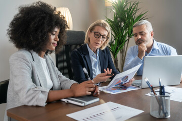 Three busy happy middle aged professional business man and two women executive leaders team using...