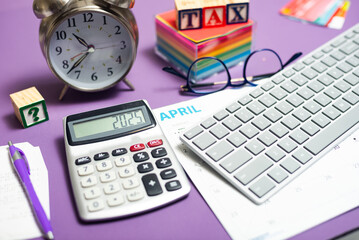 Tax filing deadline. a computer and calculator on a desk, a TAX sign and a clock.