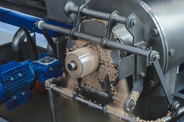 Obraz premium A machine is grinding up some material. The grinding process is in progress. The machine is made of metal and has a blue part