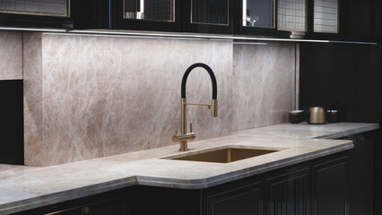 Interior of a modern kitchen with a sink and a faucet. The sink is gold and the faucet is black. The walls and countertop are beige marble, the furniture is black