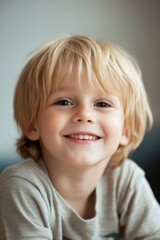 Happy young boy smiles warmly at the camera in a cozy indoor setting
