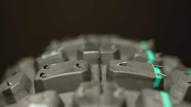 Motorcycle tire looks new. Macro close-up view of new mountain bike tire. Aggressive tread patterns for traction at speed competition with dirt bike sports. Motocross tire rotating. Extreme sports.