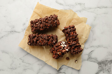 Delicious chocolate puffed rice bars on white marble table, top view