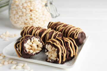 Delicious chocolate puffed rice bars on white wooden table, closeup