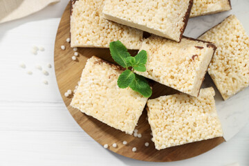 Delicious puffed rice bars and mint on white wooden table, top view