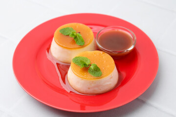Tasty puddings with caramel sauce served on white tiled table, closeup