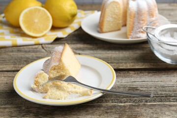 Piece of delicious lemon cake and fork on wooden table, closeup