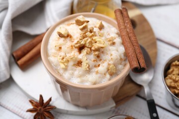 Tasty rice pudding with cinnamon served on white wooden table, closeup