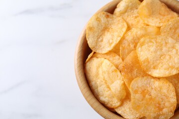 Tasty potato chips in bowl on white marble table, above view. Space for text