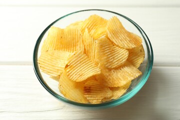 Tasty potato chips on white wooden table, closeup