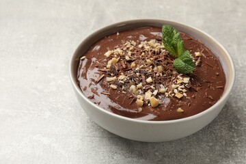 Delicious chocolate mousse in bowl on grey table, closeup. Space for text