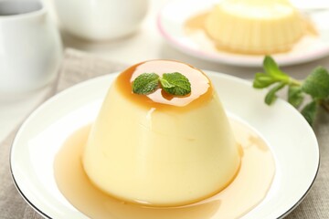 Delicious pudding with caramel sauce and mint on table, closeup