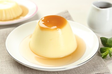 Delicious pudding with caramel sauce on table, closeup