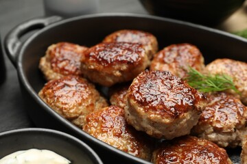 Delicious patties in baking dish on table, closeup