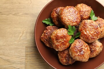 Delicious patties with parsley on wooden table, top view. Space for text
