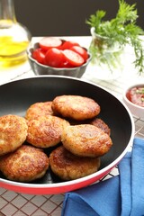 Delicious patties in frying pan, tomatoes, dill and ketchup on table, closeup