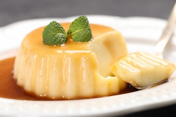 Delicious pudding with caramel sauce and mint served on table, closeup