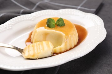 Delicious pudding with caramel sauce and mint served on gray table, closeup