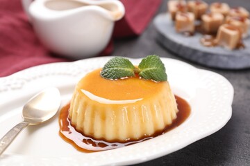 Delicious pudding with caramel sauce and mint served on table, closeup