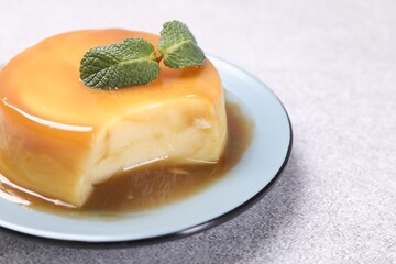 Delicious pudding with caramel sauce and mint on grey textured table, closeup. Space for text