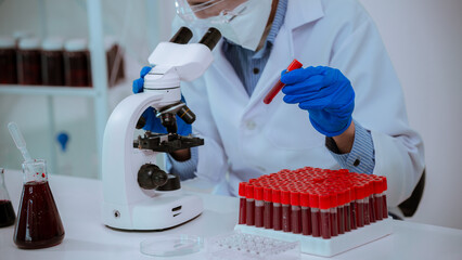 blood test tube Male scientist examines blood test tube at his DNA lab. In laboratory with holding microscope for analysis in medical research. © MrAshi