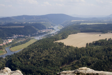 A rocky cliff peeks out from a coniferous forest and the Elbe river in the German national park Saxon Switzerland