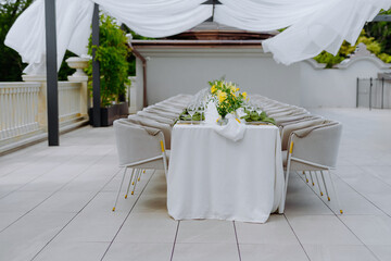 Elegant Outdoor Dining Setup with Yellow Flowers and Soft Drapery